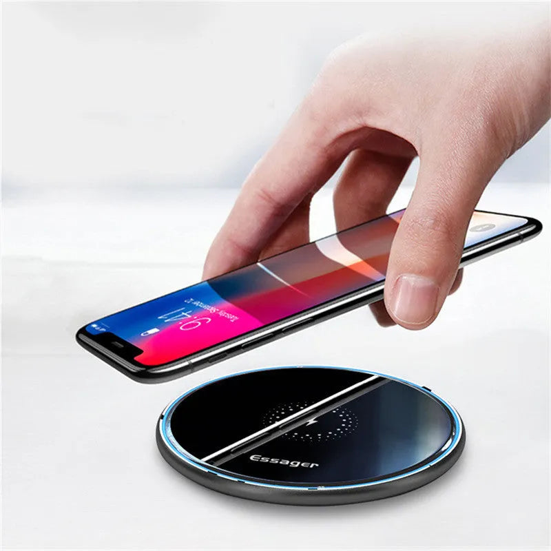 Black aluminium 15W Qi wireless fast charger for phones on a wooden desk.