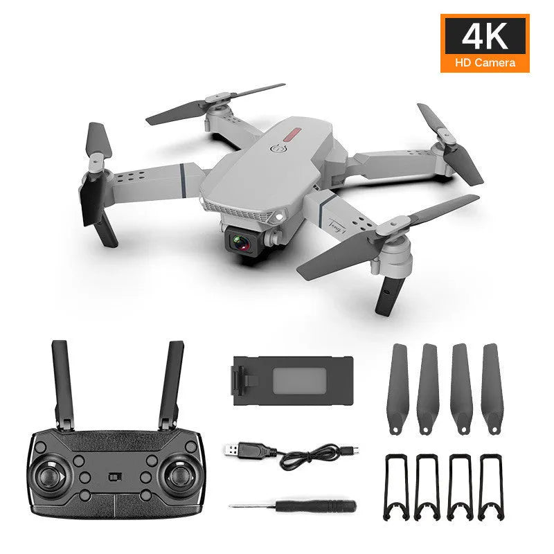 Grey foldable 4K dual camera drone with remote control, spare blades, and charging cable on a neutral background.