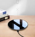 Black QI wireless charging pad on a desk, showing its non-slip silicone base.