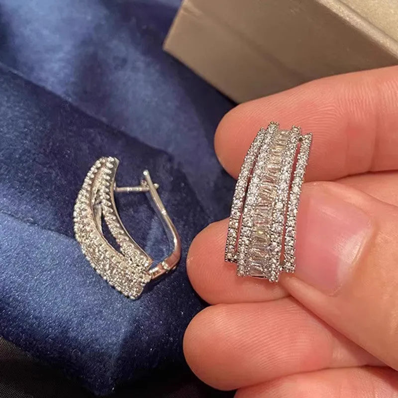 A pair of women's geometric stud earrings in white gold colour with a central inlaid zircon stone.