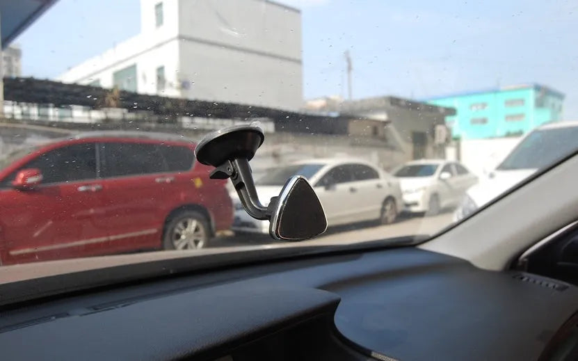 Black magnetic car phone holder mounted on a car dashboard, showing a smartphone attached.