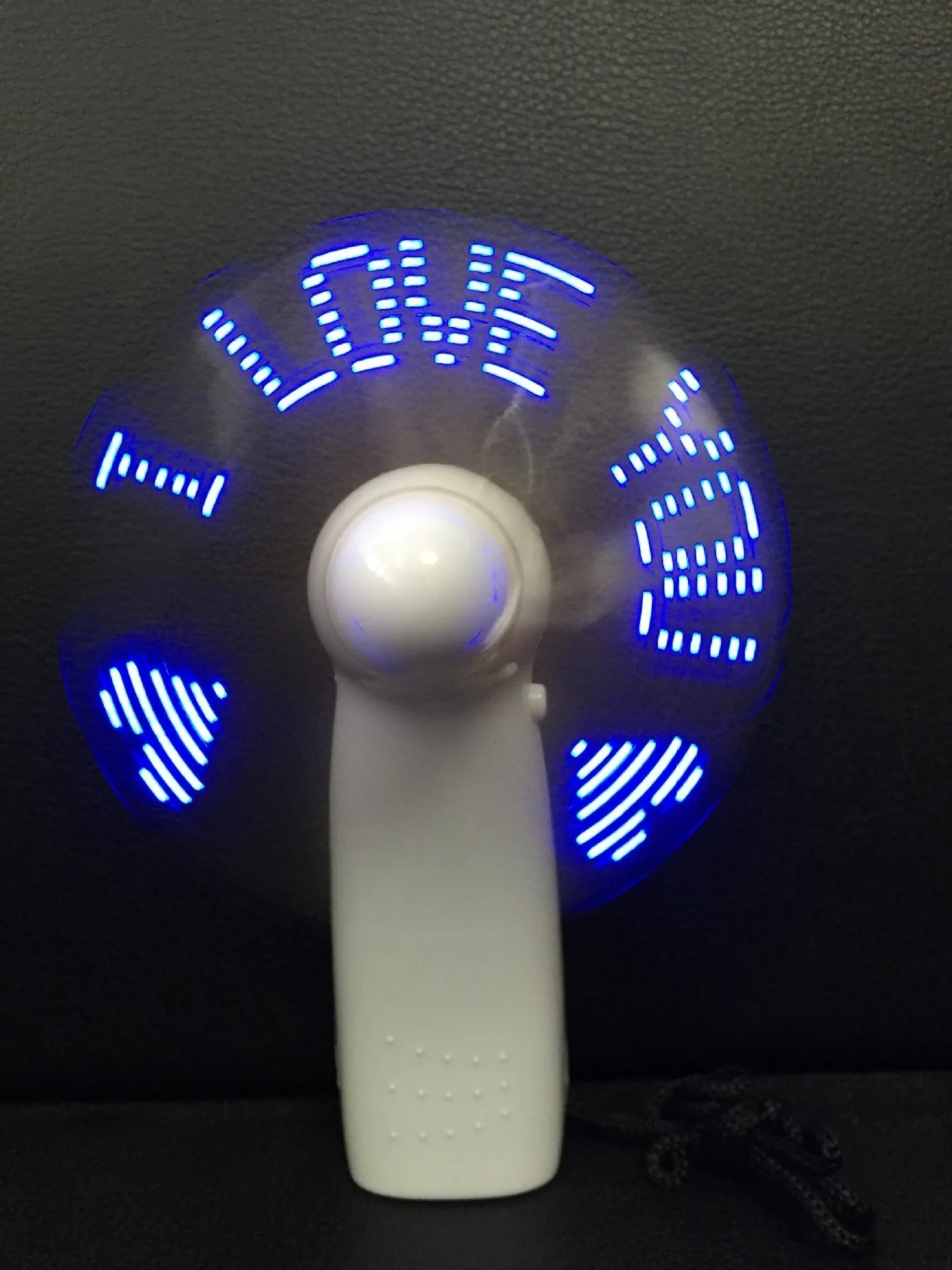 White handheld mini fan with blue and red LED love pattern flashing on its front
