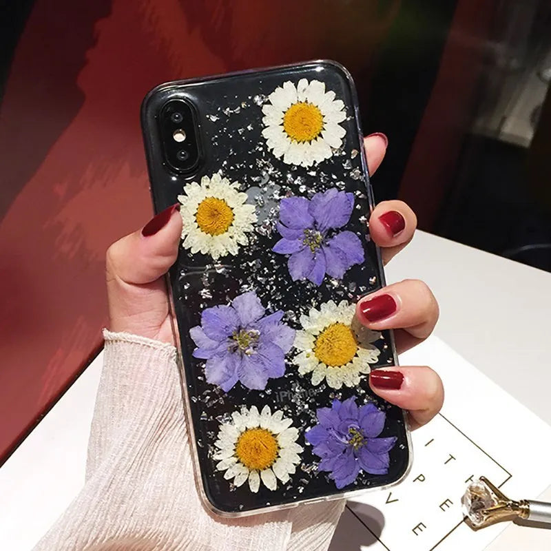 Handmade clear iPhone case with dried pink flowers preserved in epoxy resin visible through TPU back
