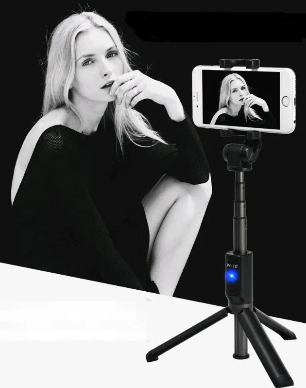 Black Bluetooth selfie stick with tripod base and remote control extended next to smartphone