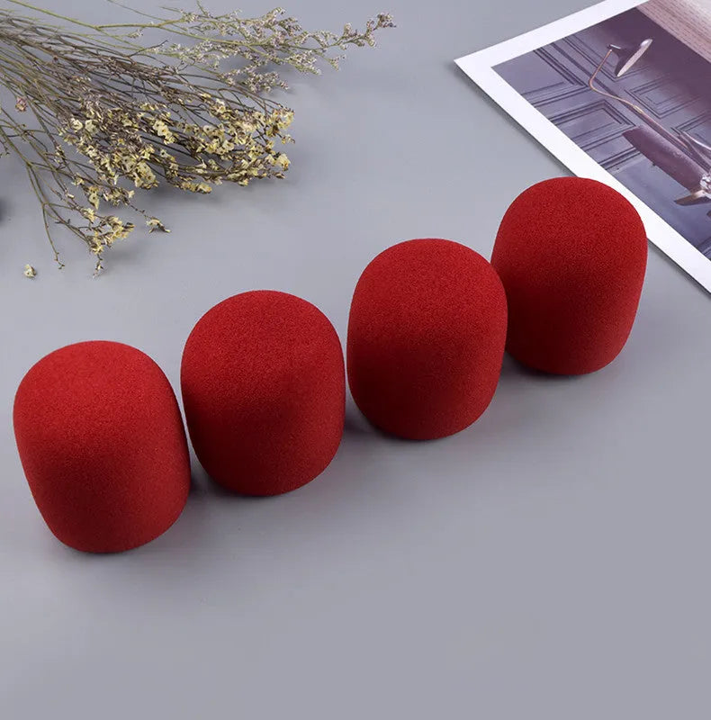 Four multicolored foam microphone windshields for handheld stage microphones on a grey background.