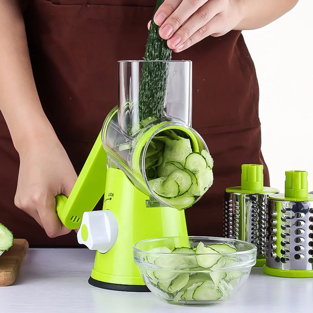 Blue green mandoline vegetable slicer with three stainless steel blades and a white suction cup base on a kitchen counter.