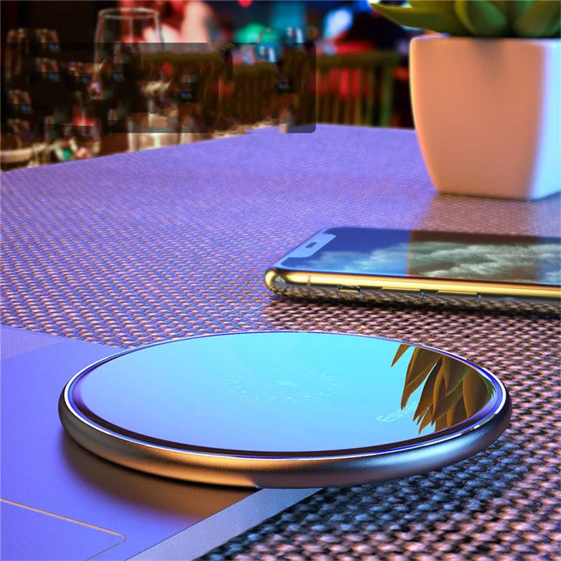 Black aluminium 15W Qi wireless fast charger for phones on a wooden desk.
