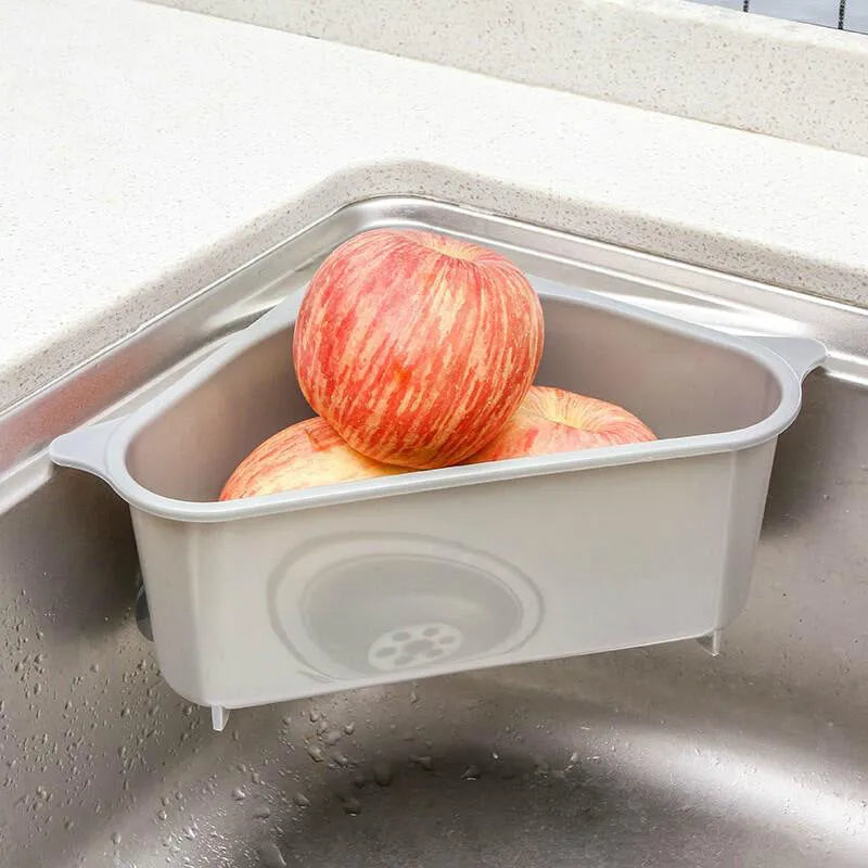 Beige plastic triangle kitchen sink rack holding a sponge and soap, hanging from a faucet.