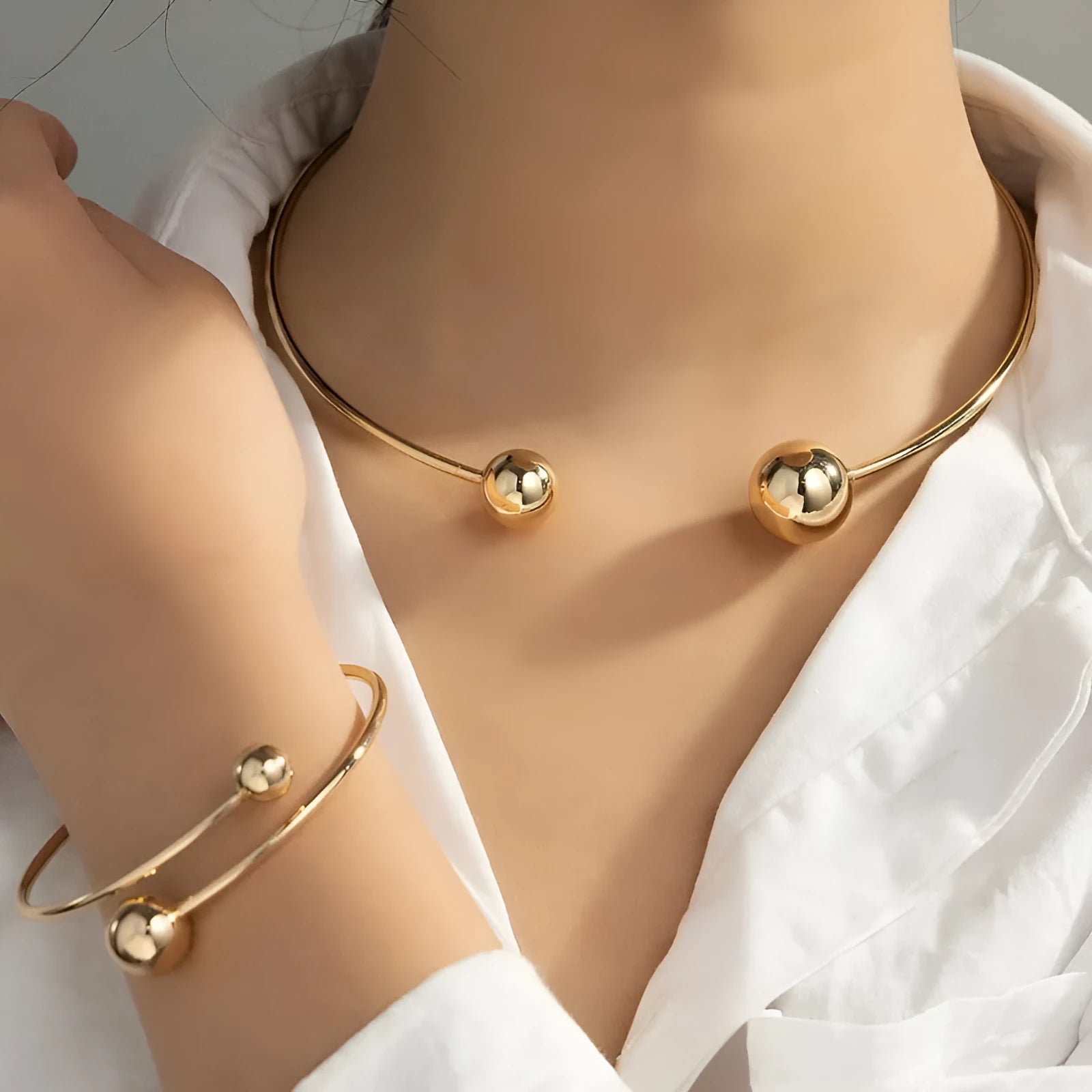 Gold silver ball dislocation thin open-end bangle bracelet with matching necklace ornament on white background