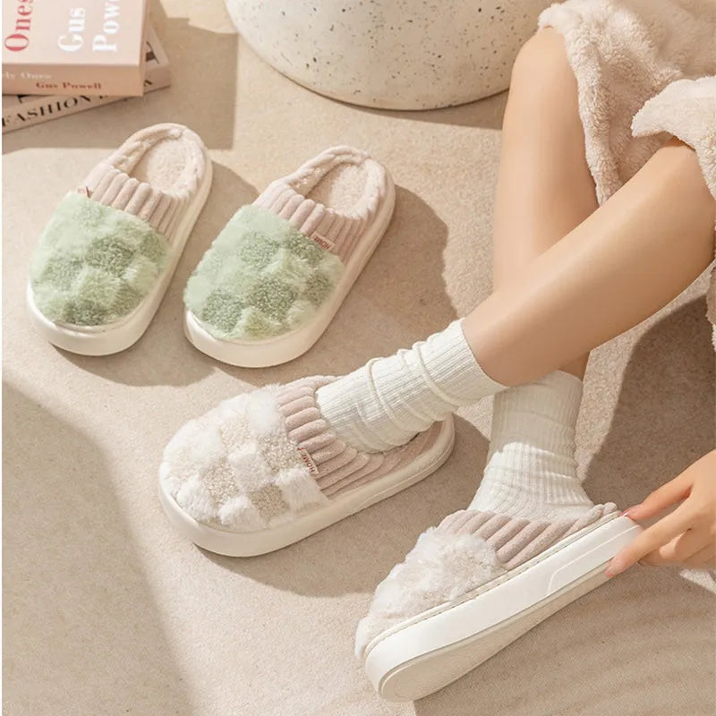 Plaid pattern women's plush indoor slippers in grey with a round toe and flat heel on a non-slip sole.