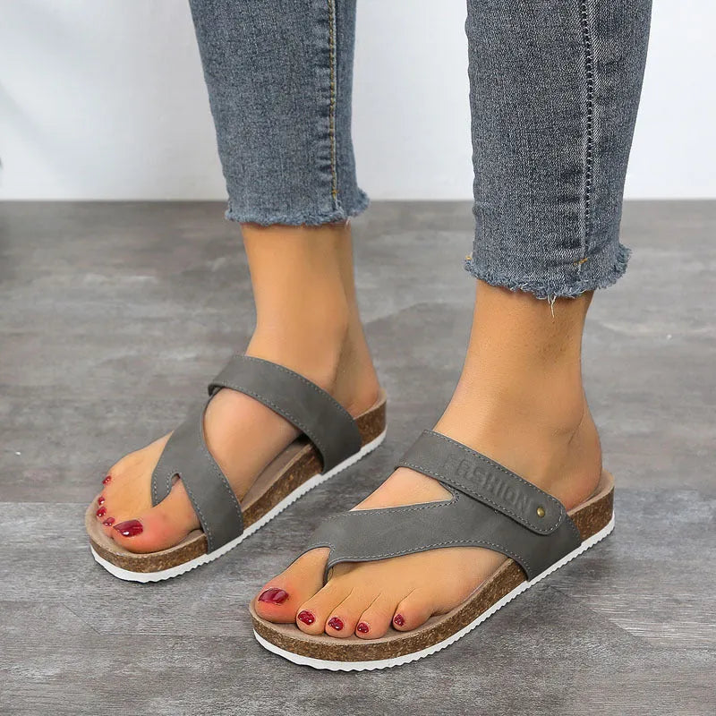 Flat toe ring flip-flops with a thick foam sole in a solid blue colour on a sandy beach.