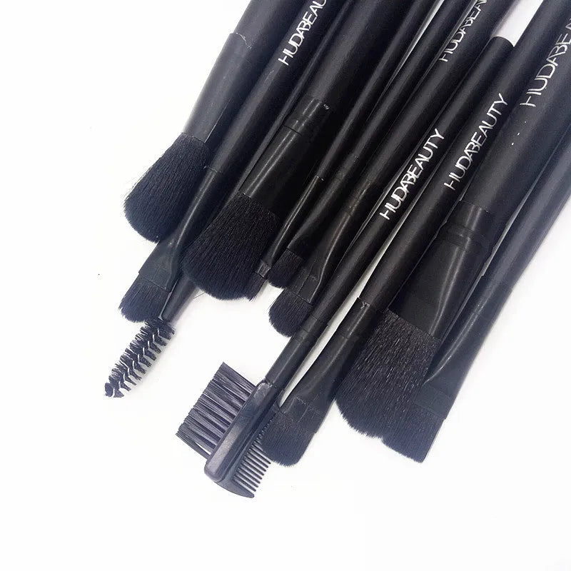 12 makeup brushes with corrugated silk nylon bristles and wooden handles in a black tin box on a flat surface.