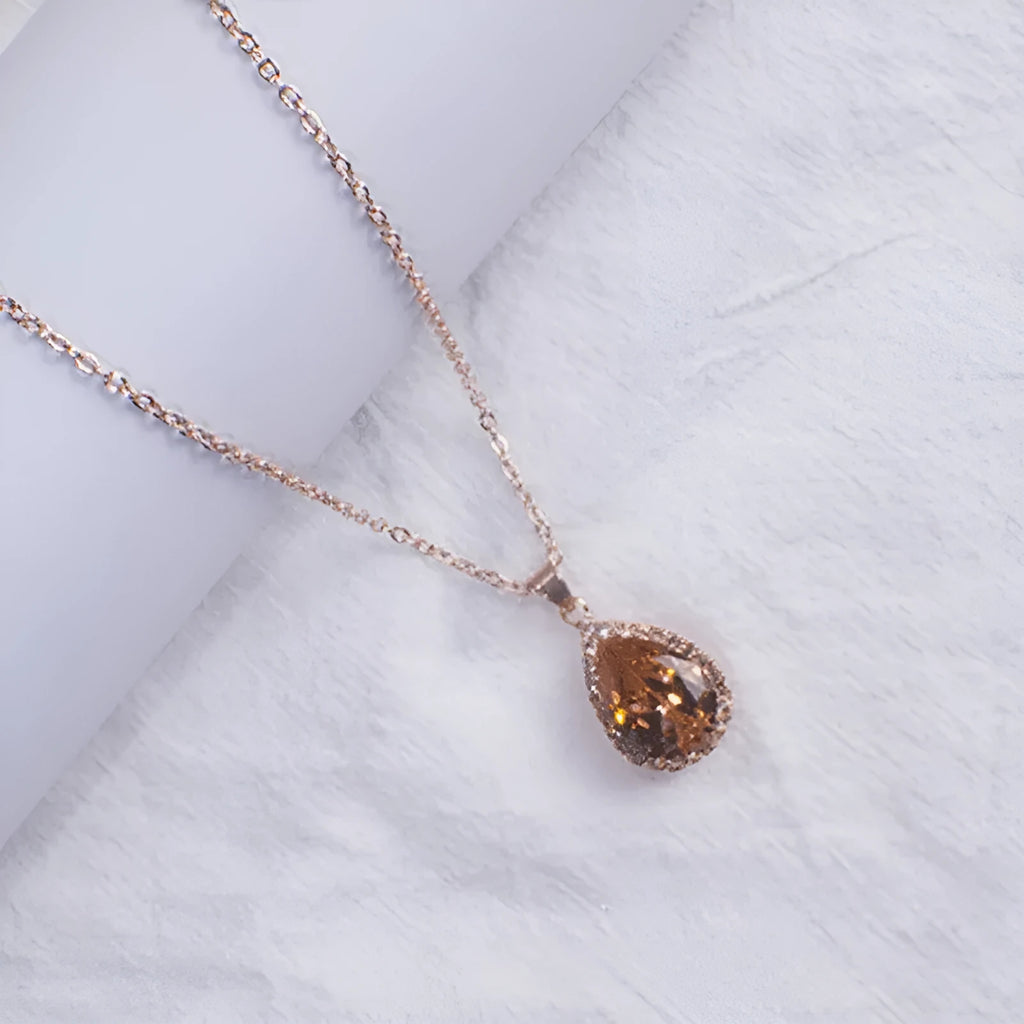 Rose gold water drop shaped necklace with geometric design and rhinestone accents in pink colour