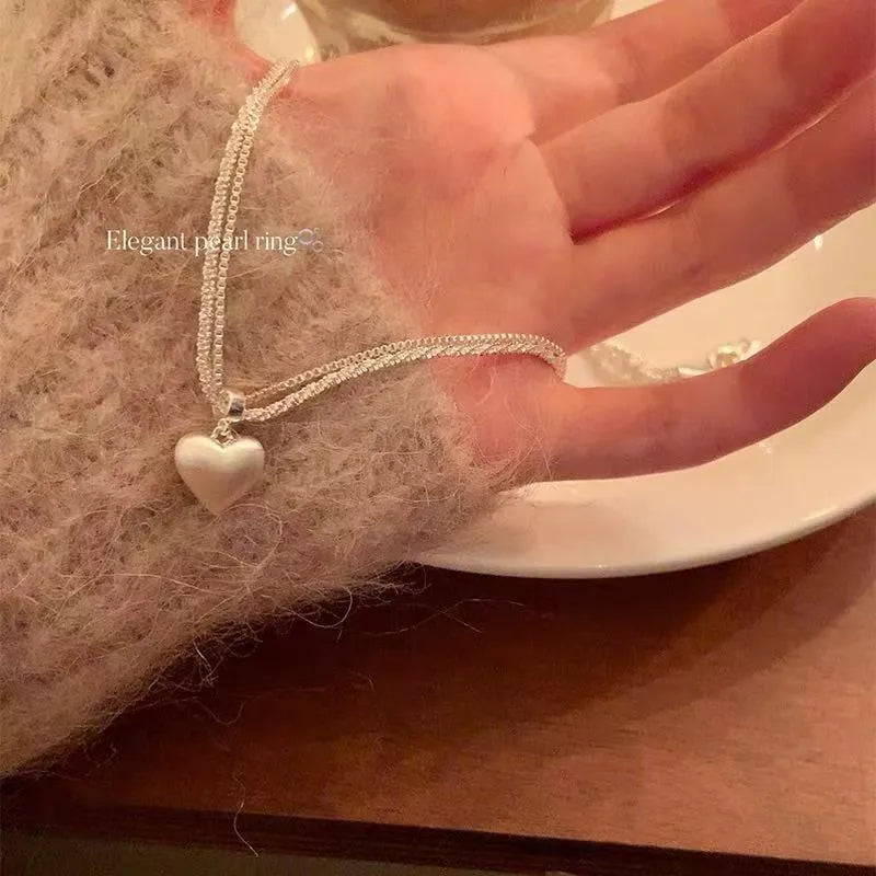 Double-layer brushed heart necklace with adjustable chain on white background