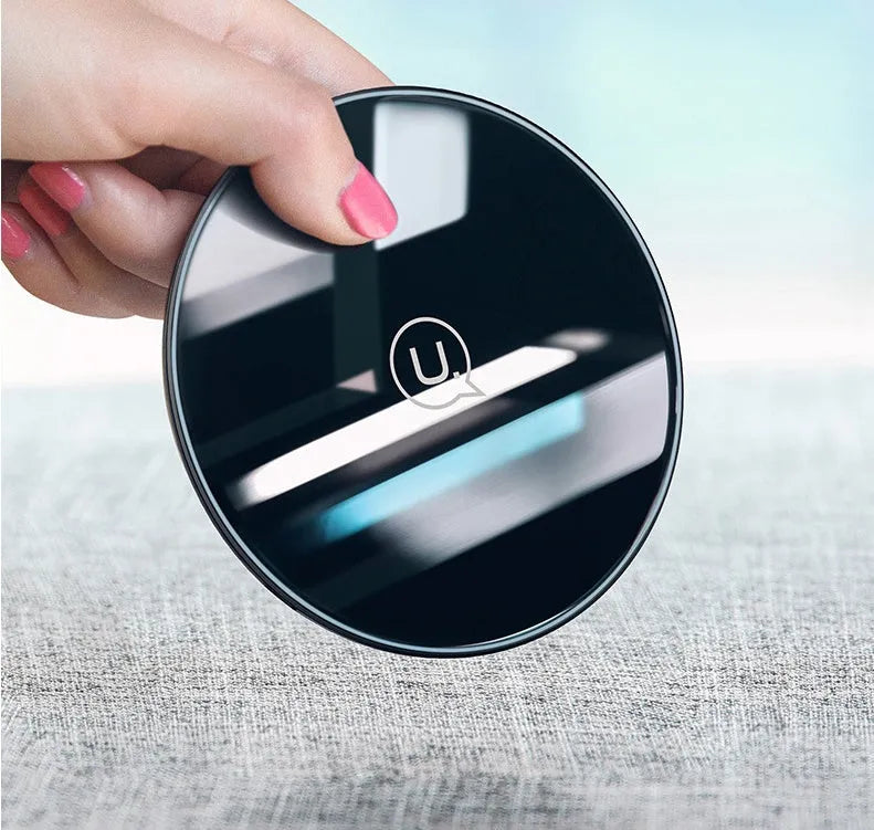 A black or white glass disc wireless charger on a table, showing its sleek design.
