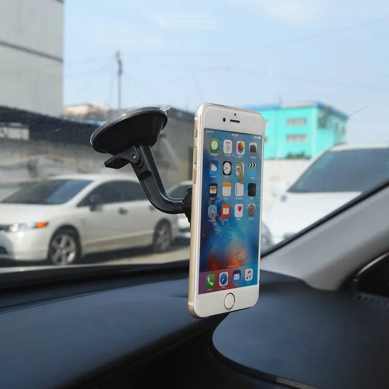 Black magnetic car phone holder mounted on a car dashboard, showing a smartphone attached.