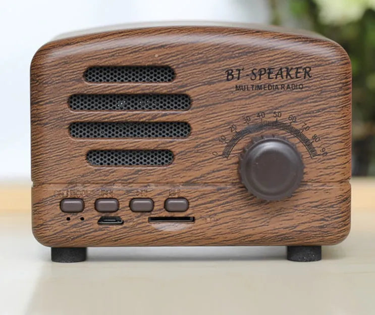 Compact vintage-style wood grain finish Bluetooth speaker on a wooden table.