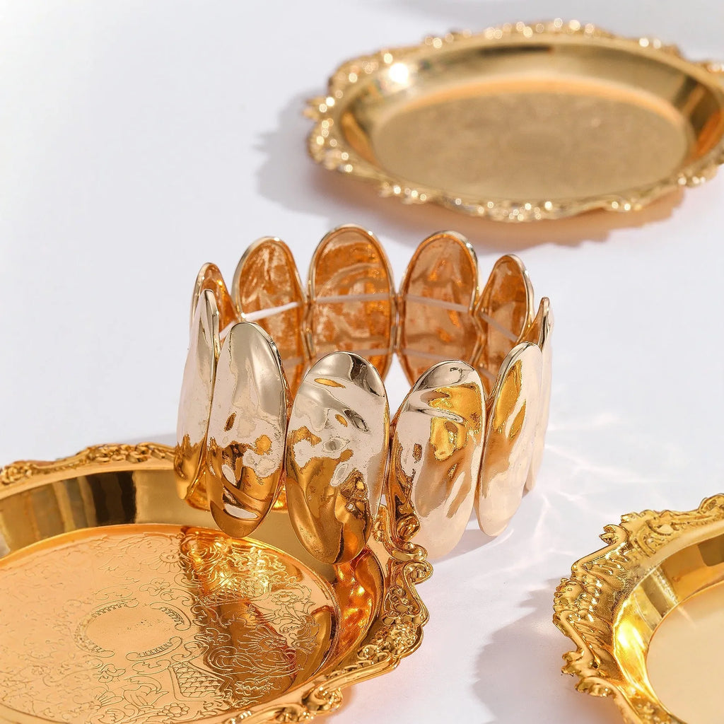 Gold exaggerated elliptical cuff bangle with 4mm band width on a neutral background