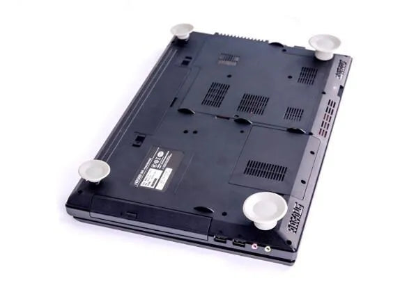Four grey plastic laptop cooling pads with silicone feet, two large and two small, on a wooden desk.
