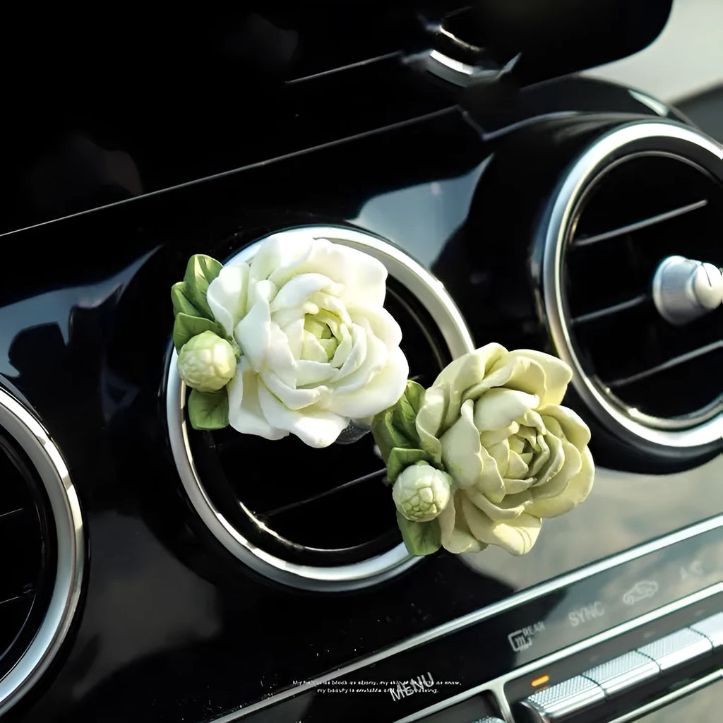 Solid jasmine car perfume diffuser clipped onto a car air vent, showing off white colour.
