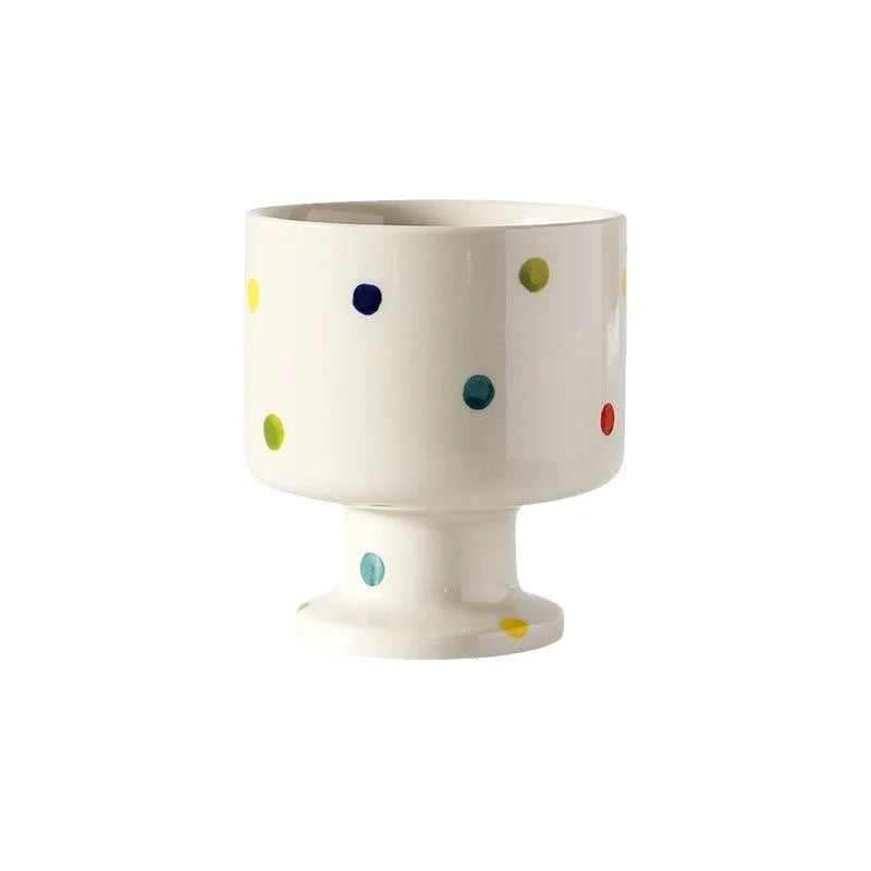 A hand-pinched ceramic mug with an irregular shape in a solid colour, shown on a table.