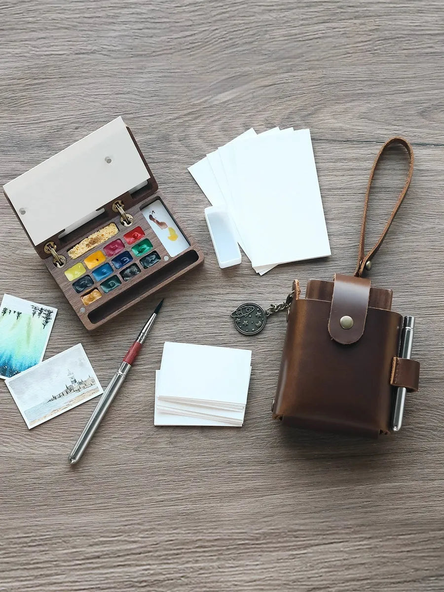 Mini walnut wood watercolour paint box open to show a set of professional paint pigments.