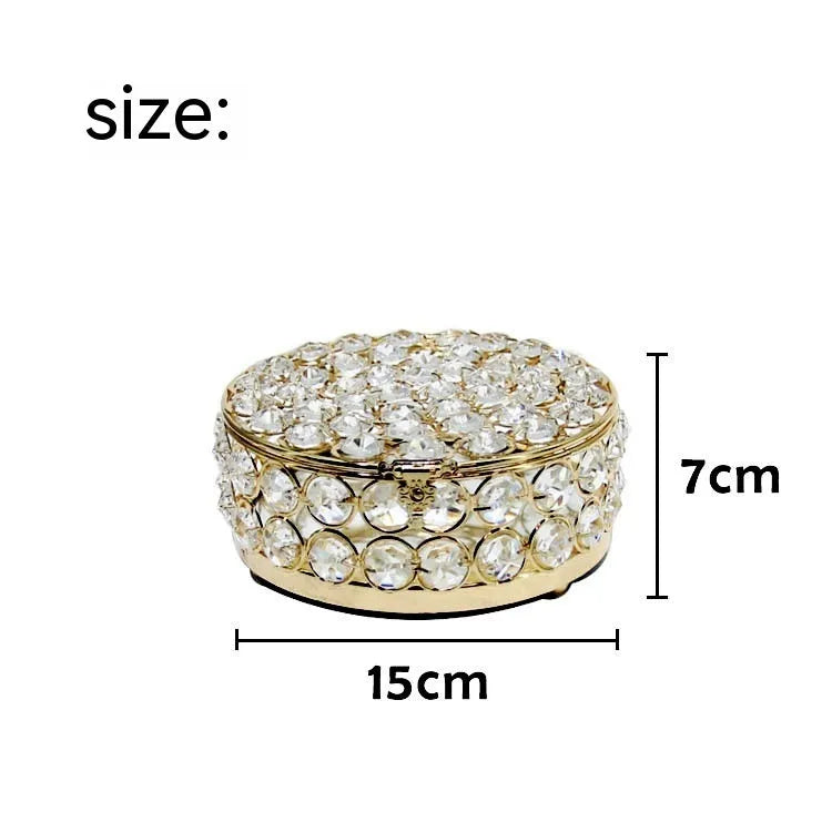 Crystal clear glass jewelry box with French gold metal frame on a table.