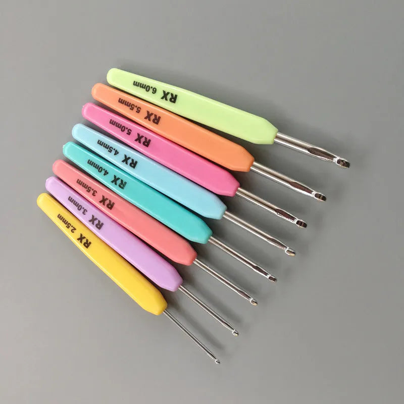 Set of 16 coloured crochet hooks with two handle types laid next to a grey PU fabric storage bag.