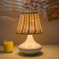Bamboo desk lamp with black iron art base, USB cable, and warm light glow on a wooden table