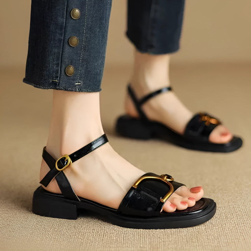 Women's black leather sandals with a thick rubber sole and buckle fastening.
