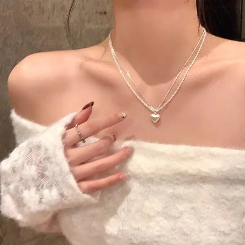 Double-layer brushed heart necklace with adjustable chain on white background