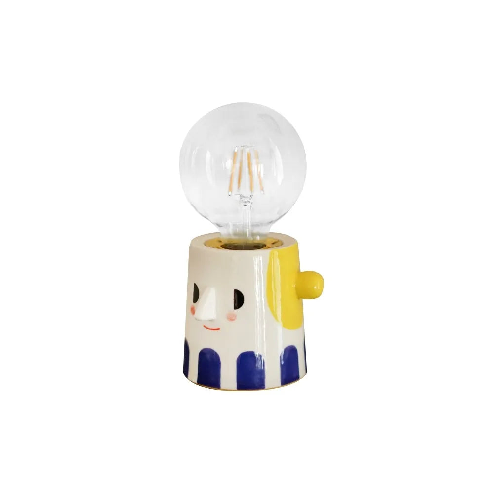 Handmade ceramic bedside lamp with a white ball headlight on a wooden table.