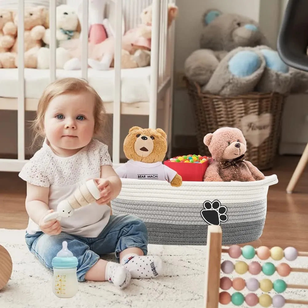 Light beige handmade woven cotton rope storage basket with a wooden handle on a wooden floor.