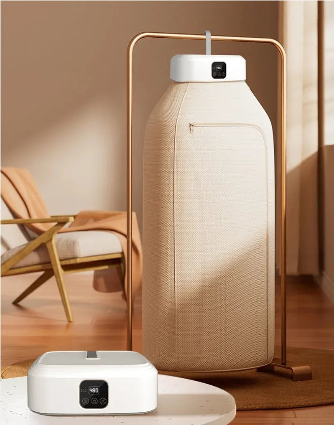 White foldable cylindrical laundry dryer with remote control on a table.