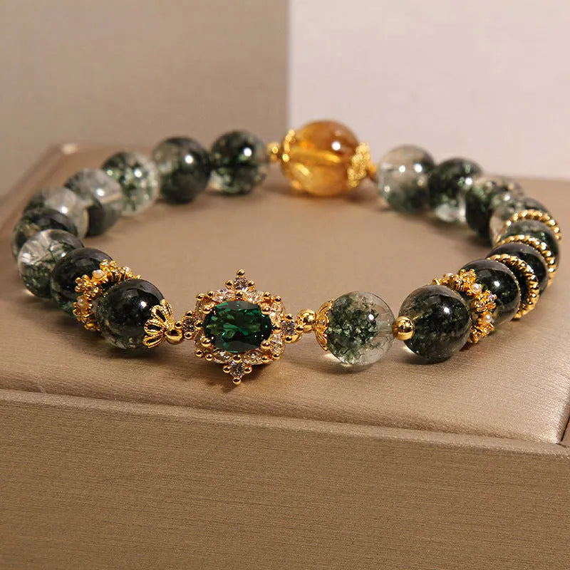 Gold electroplated women's bracelet with a green phantom quartz stone, ruby accents, rhinestones, and pearls.