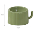 Solid green cat bowl with cactus pattern and anti-slip base on a kitchen floor.