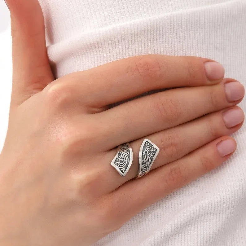 Silver-coloured adjustable minimalist women's ring with a retro design on a plain background.