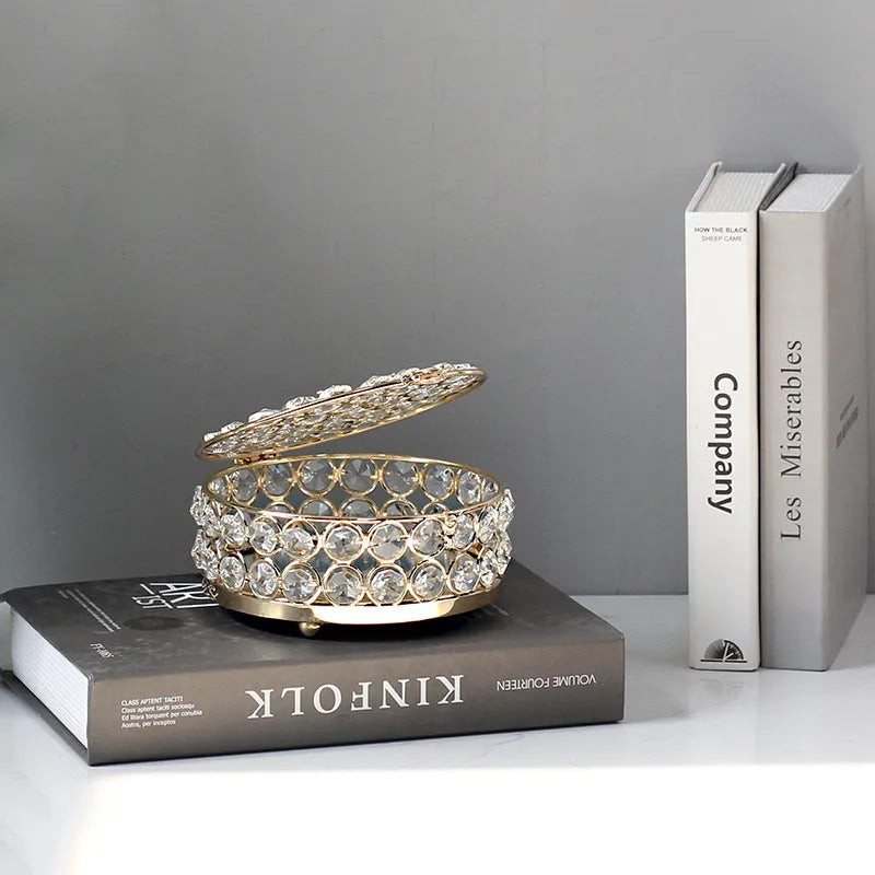 Crystal clear glass jewelry box with French gold metal frame on a table.