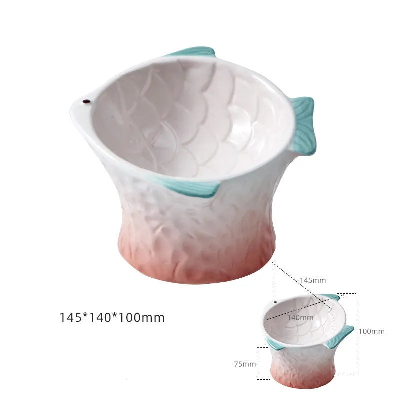 Set of blue fish-shaped ceramic cat bowls with a tilted angle on a wooden surface.