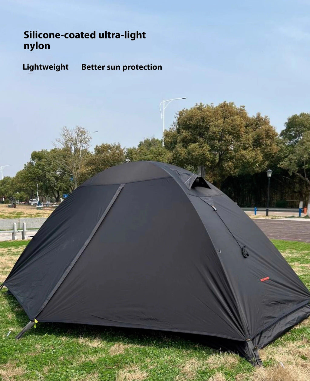 Single-person hiking tent in red pitched outdoors, showing aluminium poles and double-wall design with mesh inner.