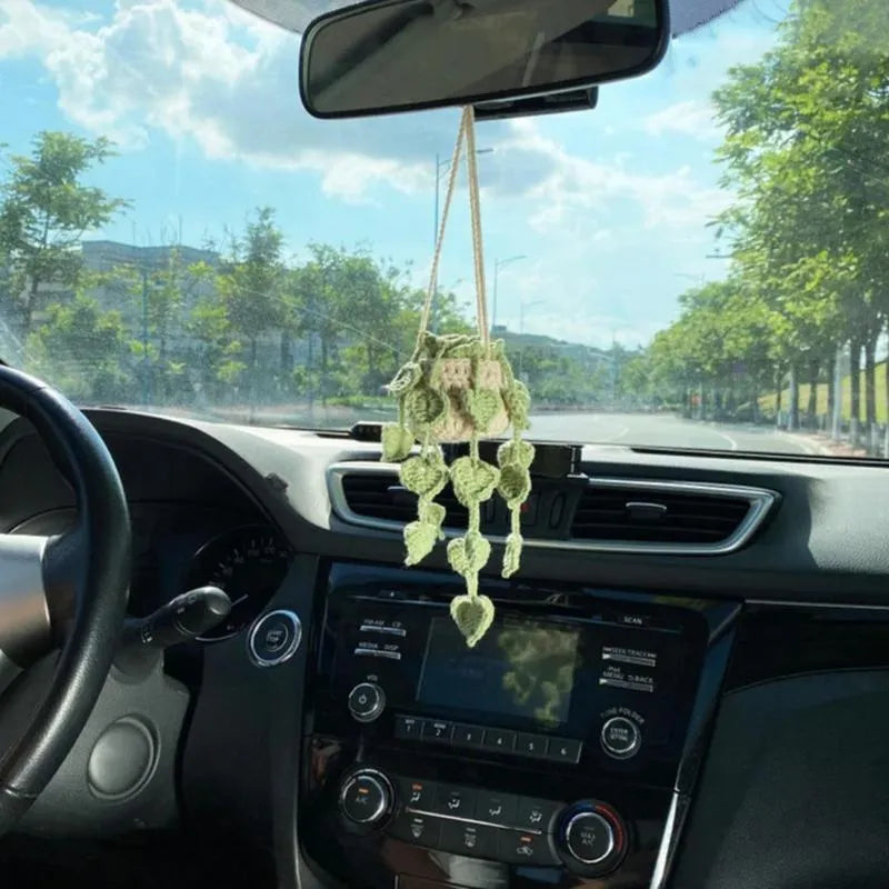 Green and white knitted wool car plant decoration with small basin and hanging rope.