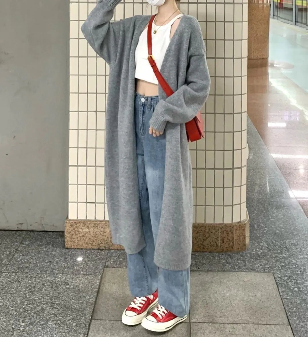 A woman wearing a loose, thick knitted chenille cardigan in a solid colour, showcasing its long sleeves and medium length.
