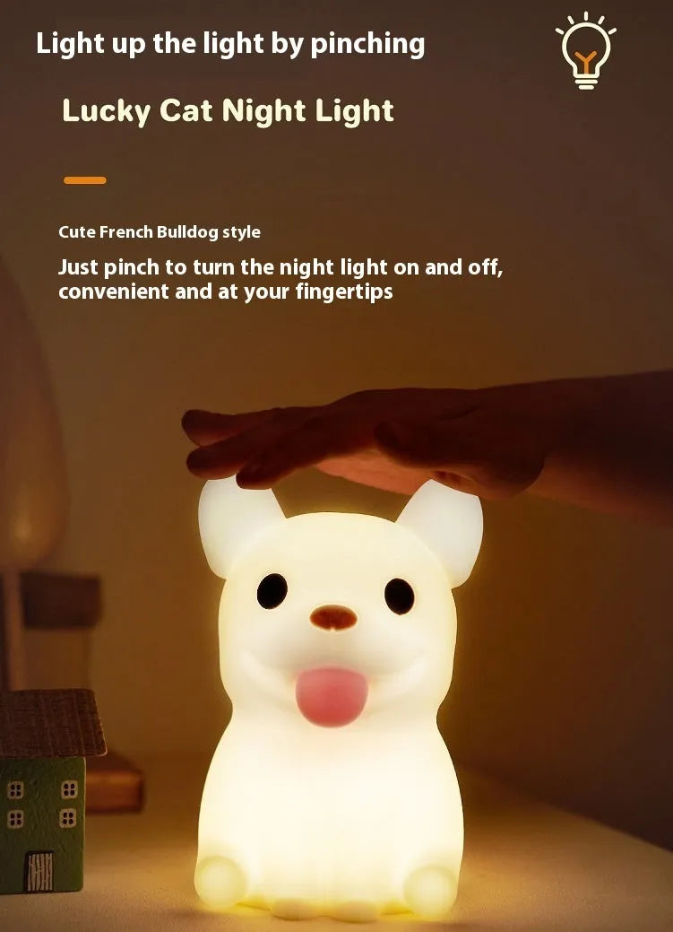 Soft silicone animal or cartoon-themed USB night light with dimming function on a bedside table.