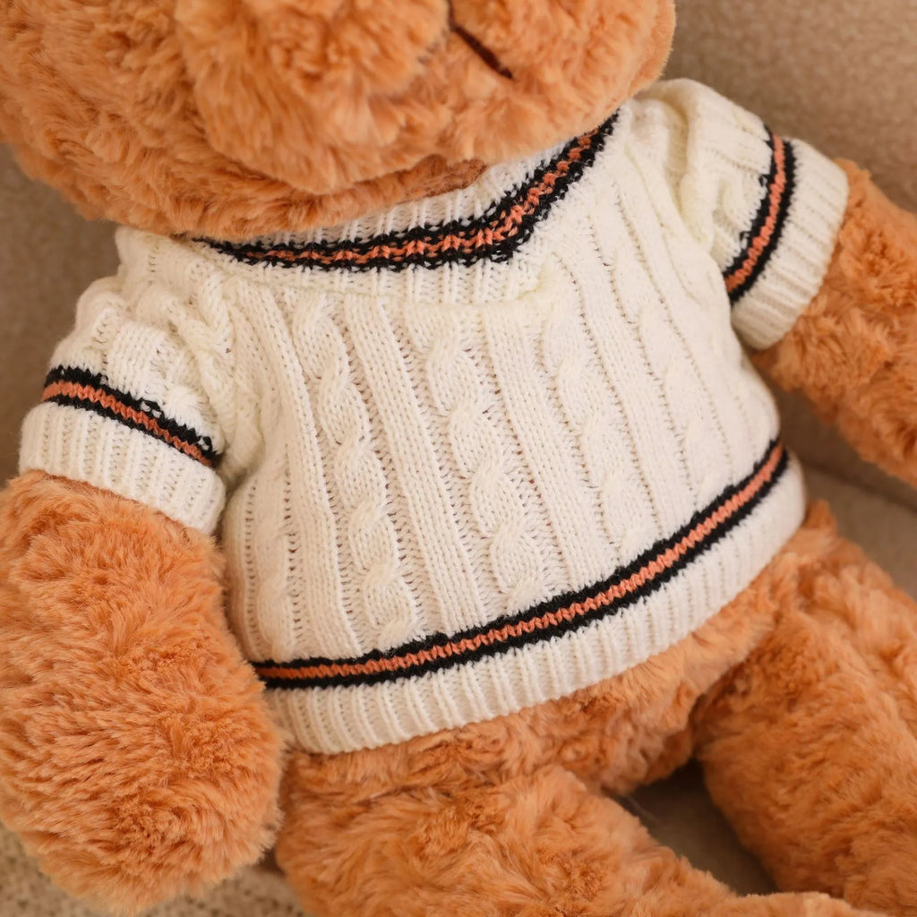 White sweater teddy bear plush toy with cloth velvet fabric and PP cotton filling, standing on a neutral background