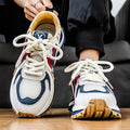 Men's casual sneaker in synthetic leather and mesh, showing round toe and lace-up front.