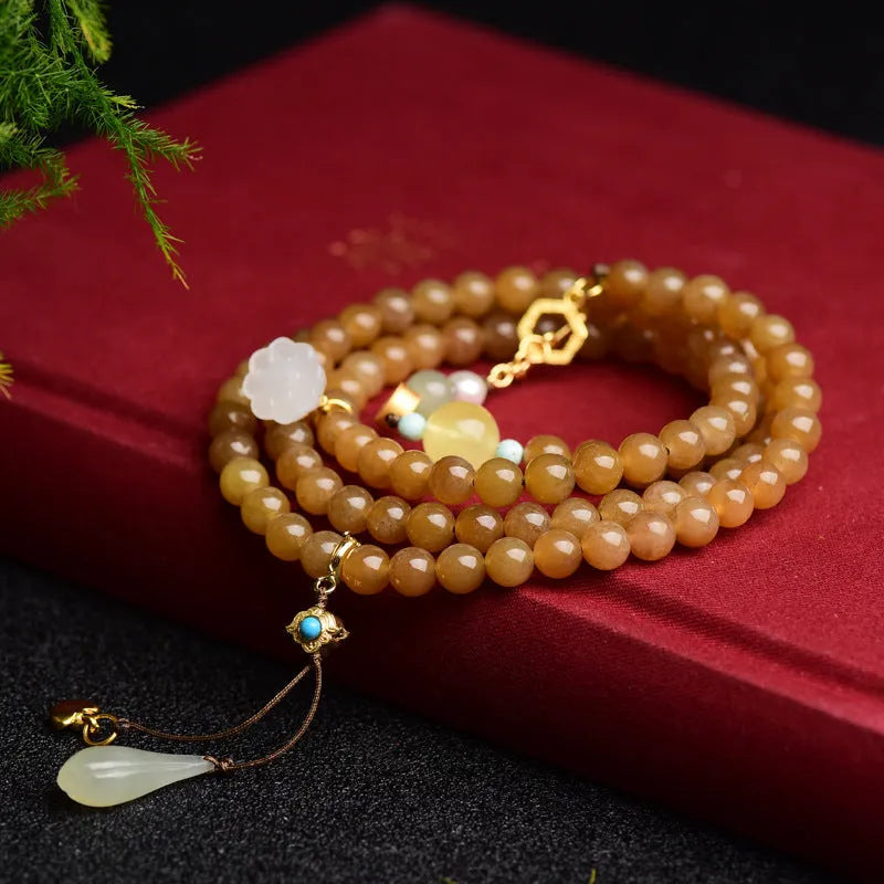 Green jade bracelet with round 6mm beads, beeswax and pine leaf charms on natural background