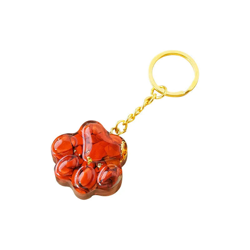 Small cat's paw shaped keychain pendant made from a natural pink crystal on a metal ring.