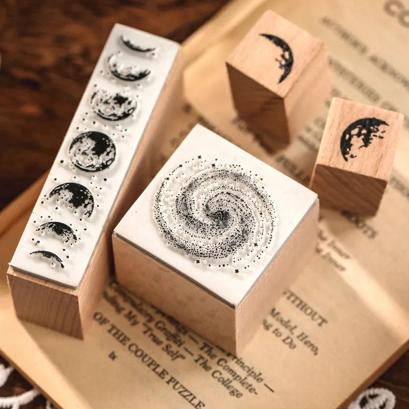 Mr Paper Seal Suit wooden stamp set showing seven stamps in either stars and moon or botanical designs on a craft table.