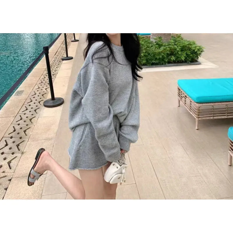 Woman wearing a loose grey knitted long sleeve sweater and matching wide-leg shorts set, front and back view.