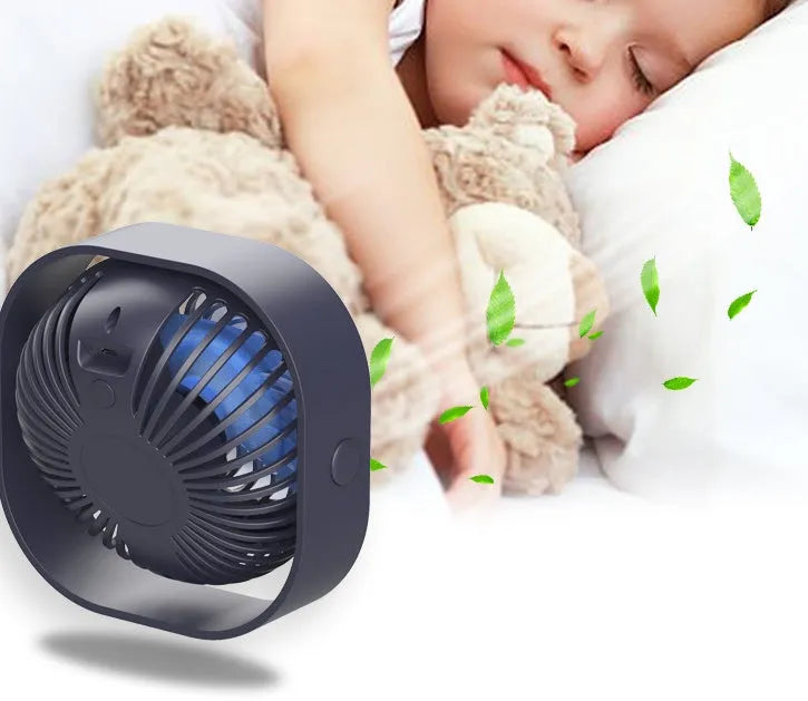 USB desk fan with 360-degree rotation in blue, on a desk next to a laptop.